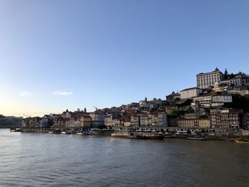 Buildings by river against sky in city