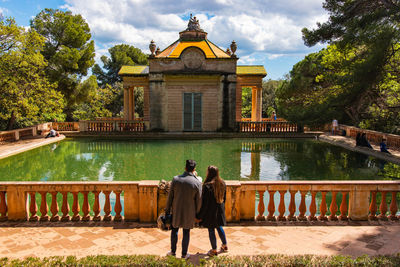 Rear view of man and woman standing against railing