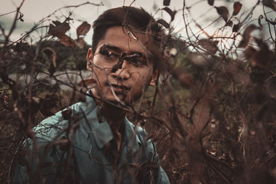 Portrait of young man with leaves on field