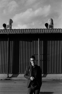 Young man smoking cigarette against building