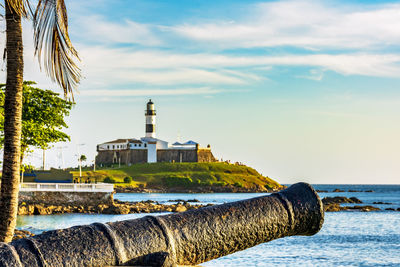 Old cannon and barra lighthouse in salvador, bahia surrounded by the sea during the late afternoon.