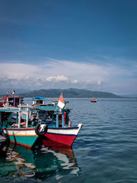 Sailboats moored on sea against sky