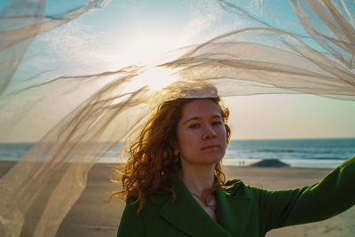 Portrait of woman at beach against sky