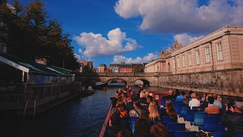 People on bridge over canal against buildings