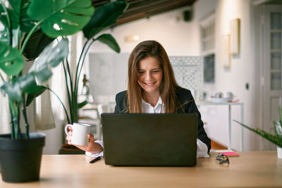 Smiling businesswoman using laptop in cafe