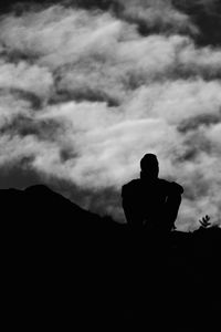Silhouette people on mountain against clouds