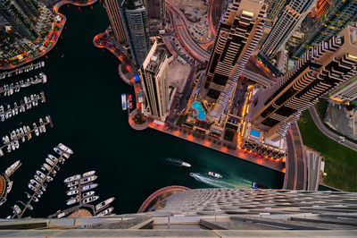 Aerial view of boats at harbor by modern buildings in city