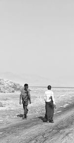 Rear view of couple on beach against clear sky