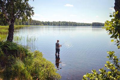 Man fishing at lake against sky