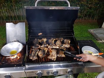 Man preparing food on barbecue grill in yard