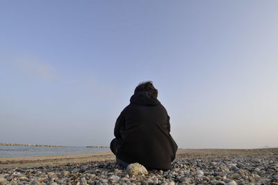 Rear view of man overlooking calm beach