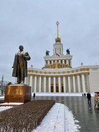 Statue in front of building against sky