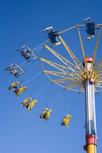 Low angle view of ferris wheel against clear blue sky