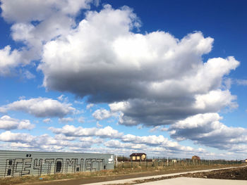 Road by buildings against sky