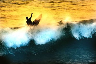 Silhouette man surfing in sea during sunset