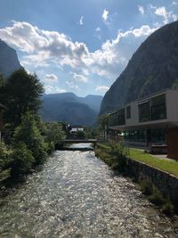 Walkway amidst buildings and mountains against sky