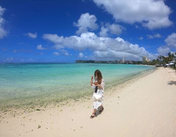 Full length of woman walking at beach against sky