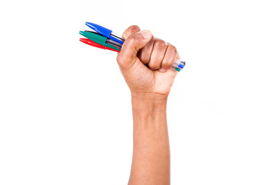 Close-up of hand holding colored pencils against white background