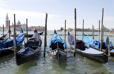 Gondolas moored at venetian lagoon against sky