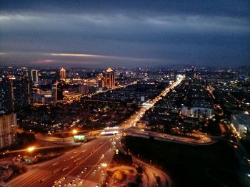 High angle view of illuminated street amidst buildings in city at night