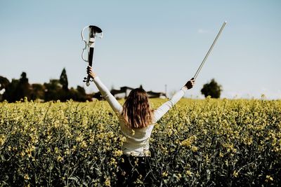 Rear view of woman with violin standing on field against sky