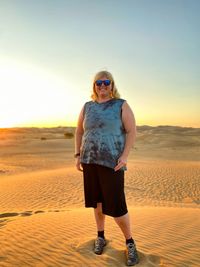 Full length portrait of man wearing sunglasses standing on desert
