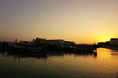 Silhouette boats moored in sea against clear sky during sunset