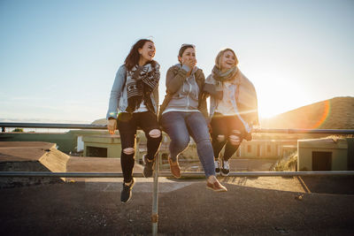 Full length portrait of happy friends against clear sky