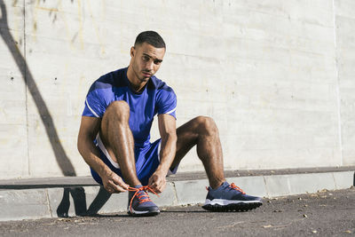 Young man sitting on wall