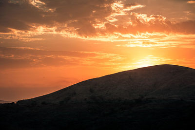 Scenic view of silhouette mountains against orange sky