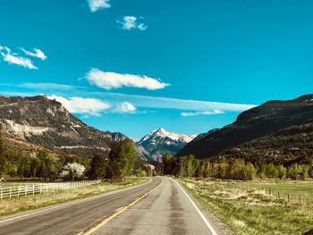 Empty road along landscape and mountains against sky