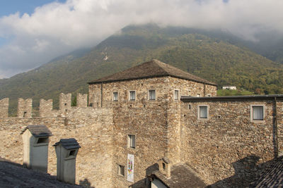 Old building by mountains against sky