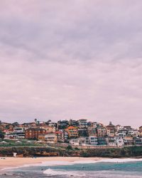 View of cityscape by sea against sky