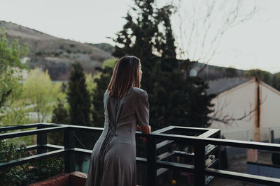 Woman standing by railing against sky