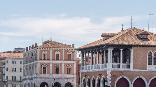 Buildings in town against cloudy sky