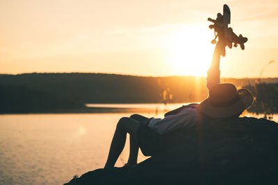 Close-up of silhouette statue against sea during sunset