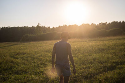 Rear view of man on grass against sky