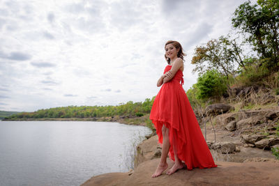 Woman standing by red umbrella against sky