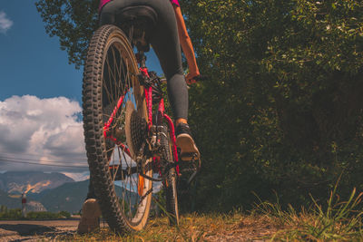 A low-angle close-up of a female cyclist riding a bicycle on a rural road in the french alps