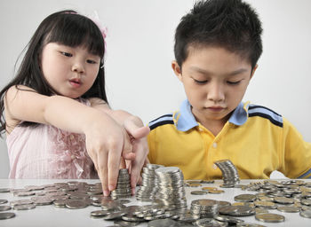 Children counting coins on table against white background