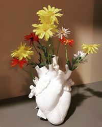 Close-up of white flowering plant in vase against wall