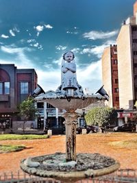 Statue against buildings in city against sky