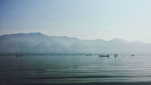 Scenic view of lake and mountains against sky during foggy weather