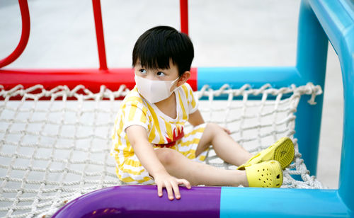 Young boy wear mask playing in the park. young boy climbing a rope net outdoor on the kid playground