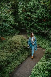 Full length of woman walking on footpath amidst forest