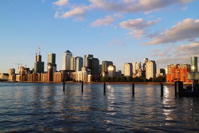 City at waterfront against cloudy sky