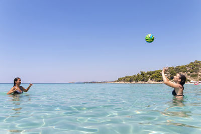 Happy teenagers playing volleyball in water at the vacation and fun