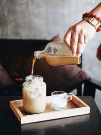 Close-up of hand pouring coffee cup on table