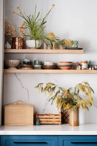 Kitchen shelves with ceramic utensils, fresh flowers and ceramic figures of mushrooms and beetles