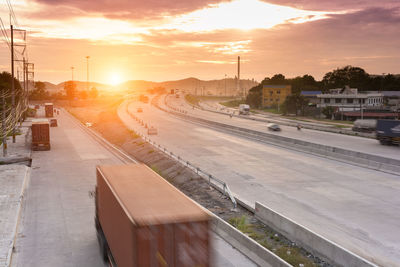 Road by city against sky during sunset